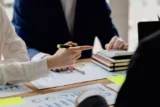 Uma mesa em uma sala de conferências da empresa tem um grupo de empresários presentes.