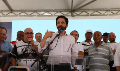 Prefeito reeleito Ricardo Nunes em discurso, com diversos apoiadores atrás no palanque.