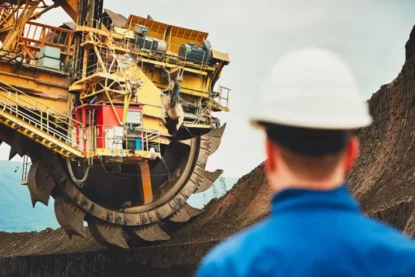 Imagem mostra máquina gigante sendo supervisionada por trabalhador de mineradora. (Imagem: Chalabala em Adobe Stock)