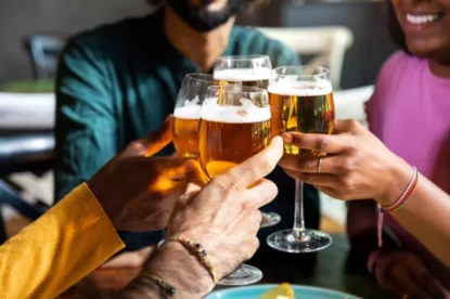 Closeup de amigos brindando com cerveja dentro de casa. Amigos se divertindo no bar torcendo com cerveja. Comemorando. Conceito de amizade.