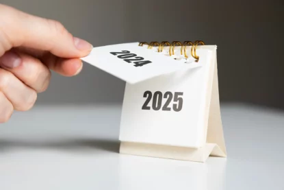 Imagem mostra detalhe de mão trocando folha de calendário de 2024 para 2025.