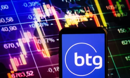 Aplicativo do BTG Pactual contra tela com gráfico do mercado monetário.