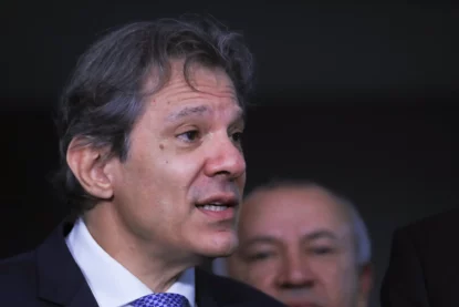 Fernando Haddad durante entrevista em ambiente institucional, com expressão séria e falando sobre isenção do Imposto de Renda e pacote fiscal.